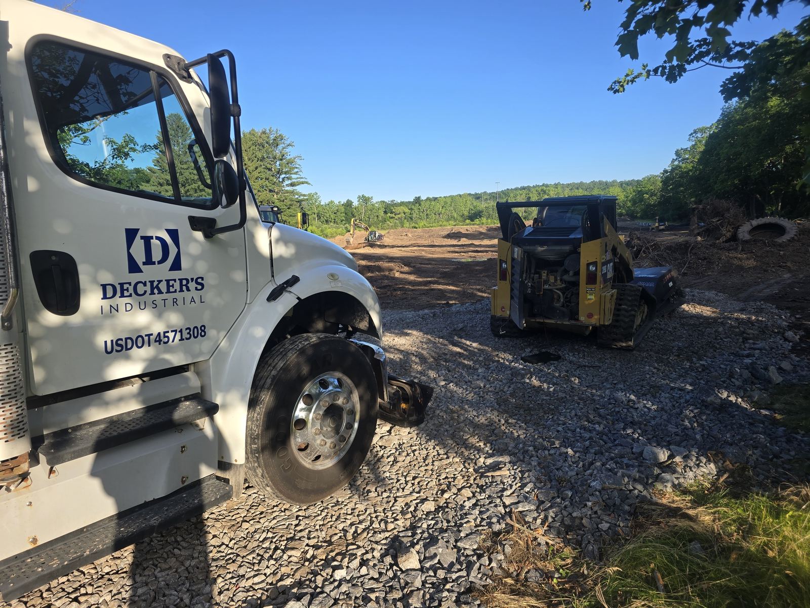 Decker's Industrial service truck door with the company logo, parked beside a CAT track loader on a Capital Region site