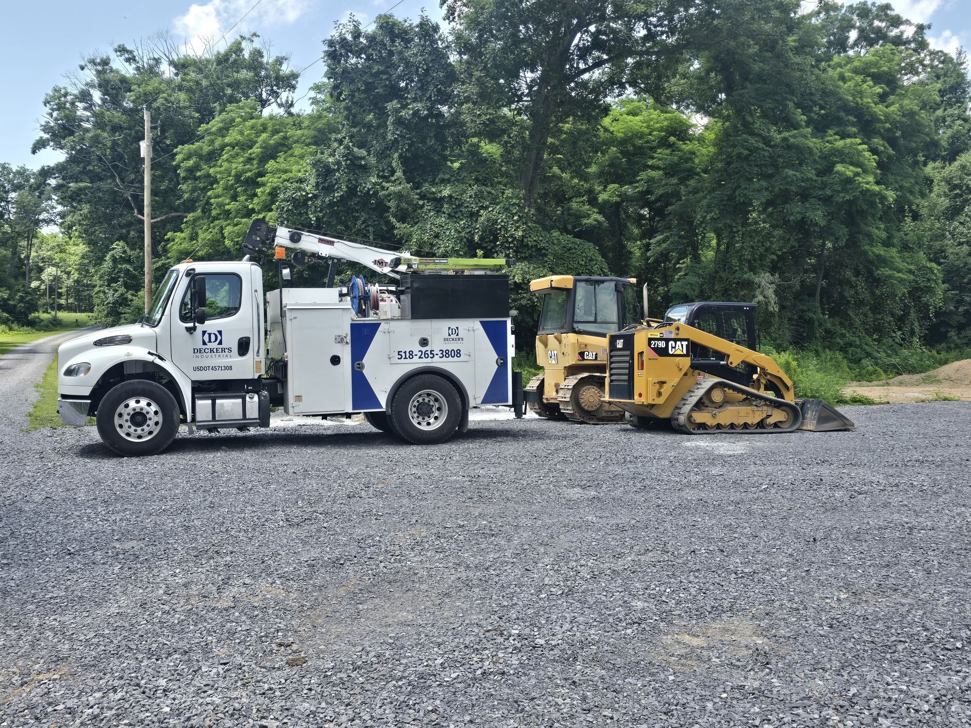 Decker's Industrial service truck with boom crane parked beside a CAT 279D track loader and a CAT dozer at a Capital Region job site