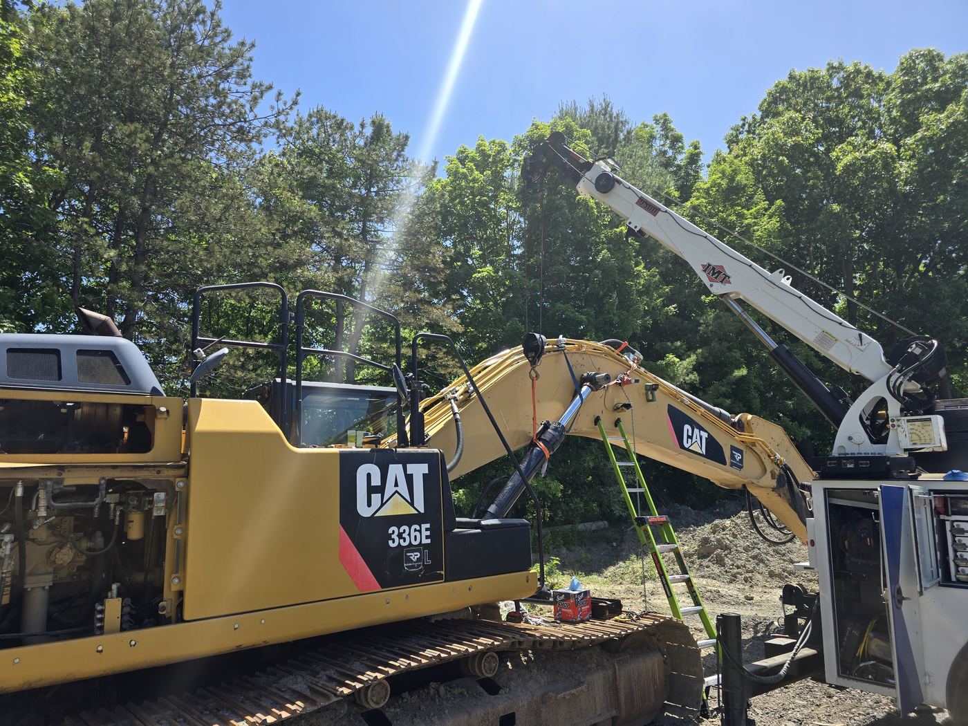 Boom truck holding the arm of a CAT 336E excavator while Jake Decker performs a field repair