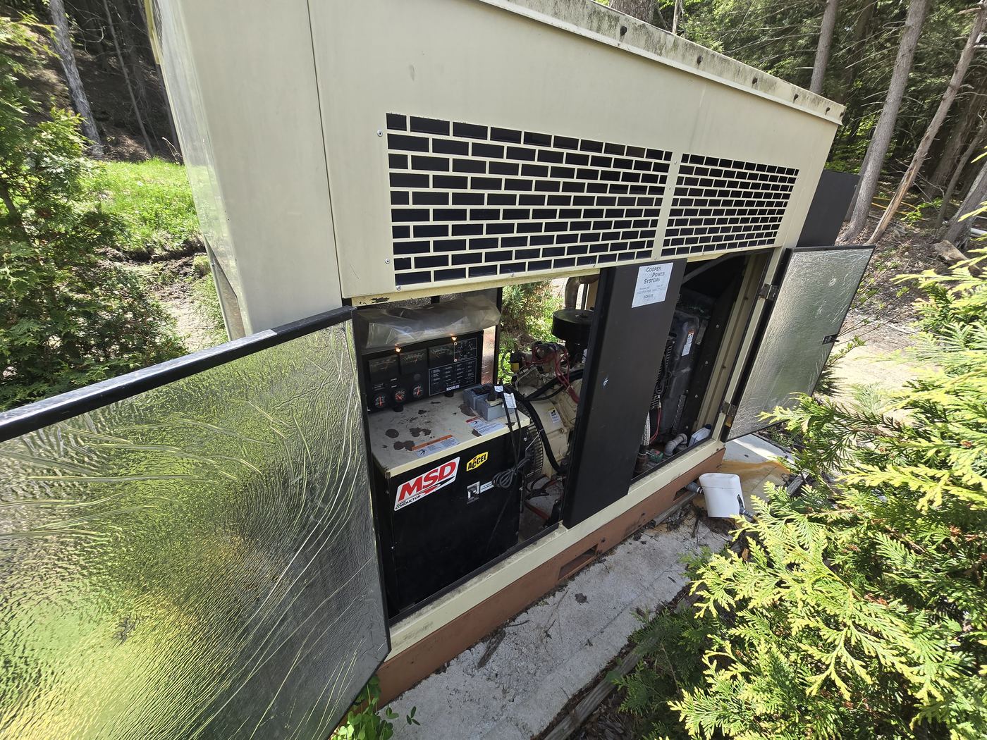 Enclosed Kohler standby industrial generator with access doors open for preventative maintenance